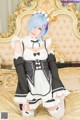 A woman in a maid outfit sitting on a bed.