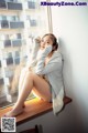 A woman sitting on a window sill with her legs crossed.