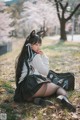 A woman in a school uniform sitting on the ground.