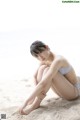 A woman in a bikini sitting on the sand.