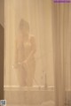 A naked woman standing in a bathtub with a shower curtain.