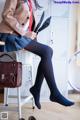 A woman sitting on a chair with a handbag and a pair of shoes.