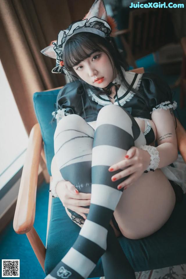 A woman in a black and white outfit sitting on a chair.