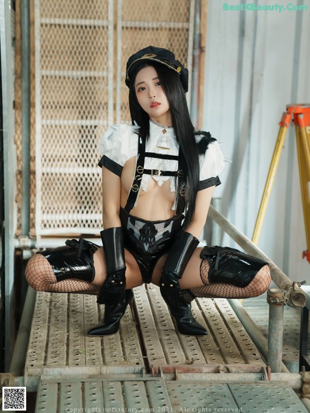 A woman in a black and white outfit sitting on a metal platform.