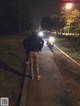 A woman walking down a street at night with her back to the camera.