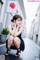 A woman in a black dress sitting on the ground.