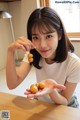 A woman sitting at a table holding a bunch of fruit.