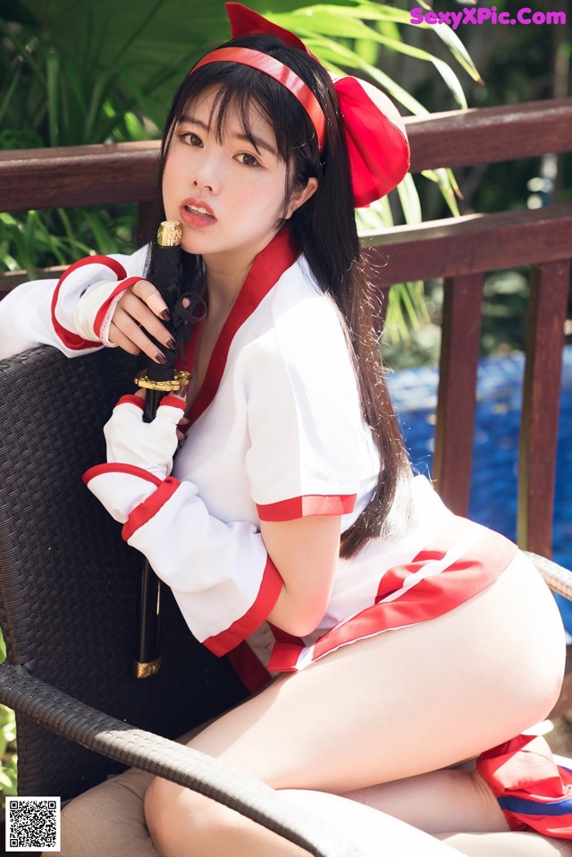 A woman in a red and white outfit holding a sword.