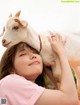 A woman holding a goat on her head. 